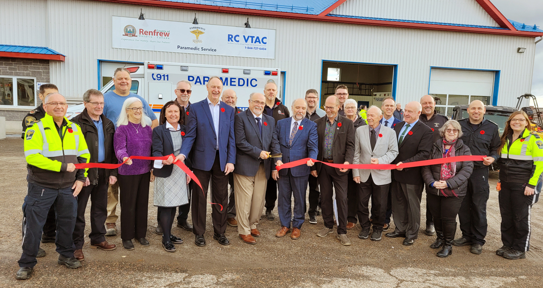 Large group of people cutting a ribbon to mark official building opening