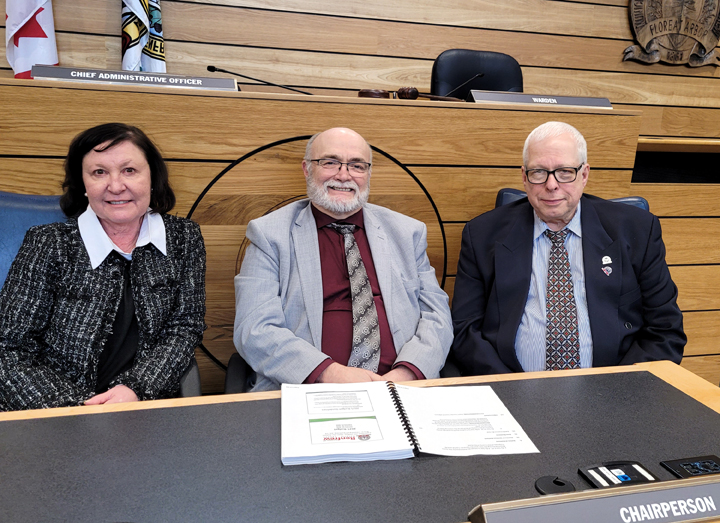 three people sitting at a desk with a budget document in front of them